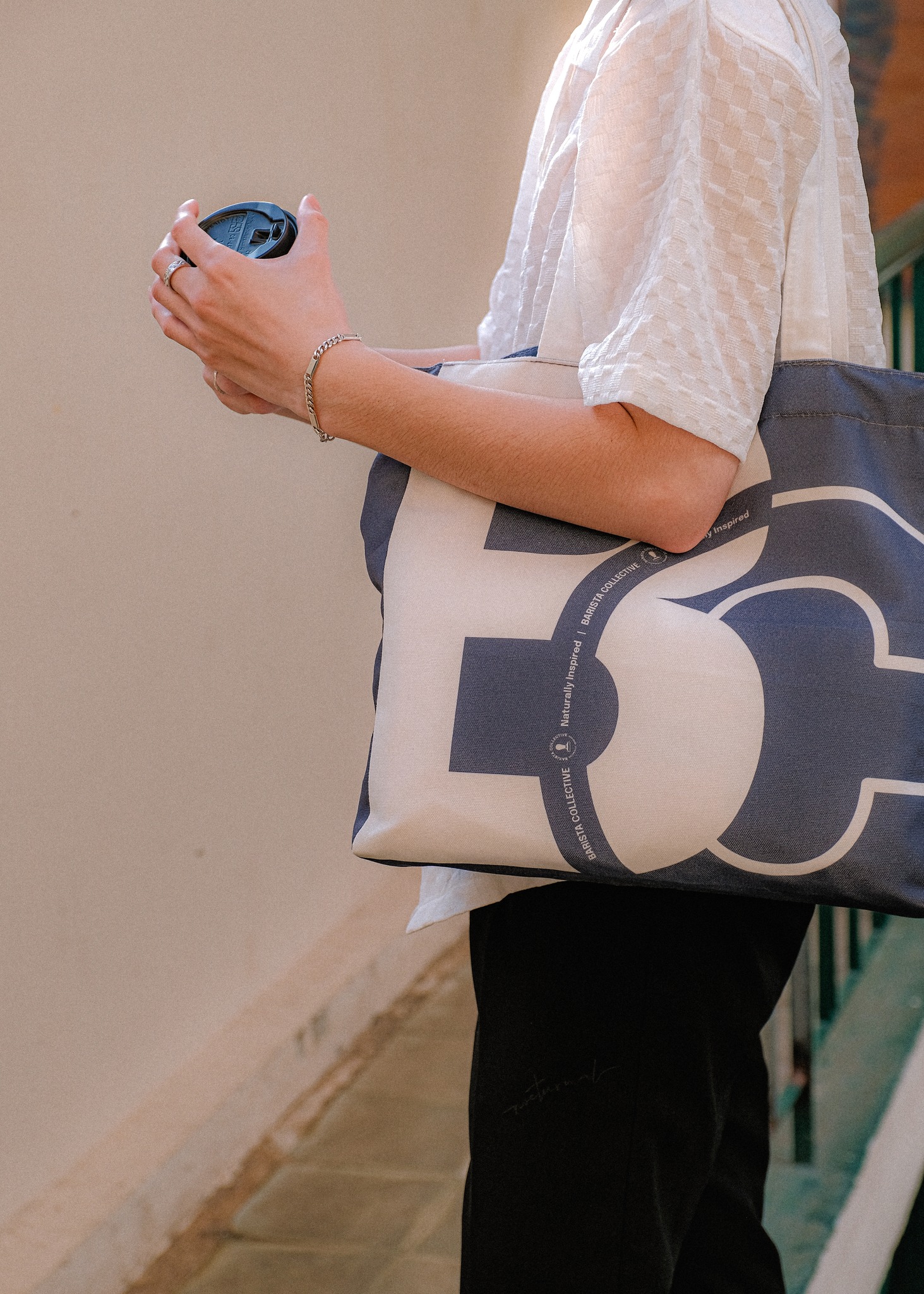 The Navy Tote carried on the shoulder with a morning coffee