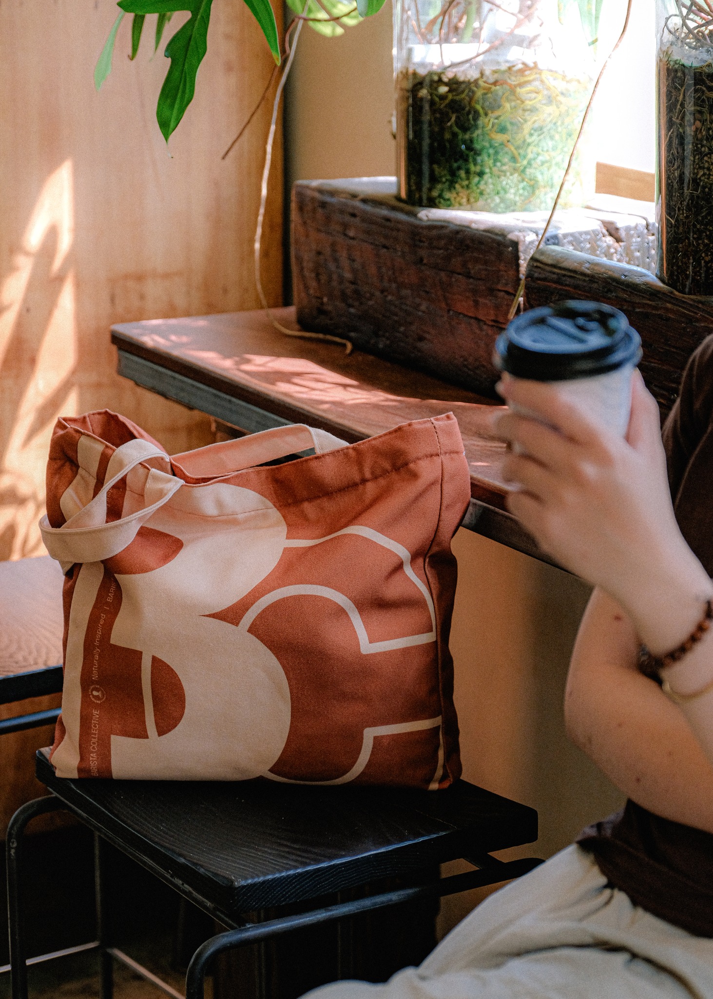 A rust tote resting on a café stool beside a fresh cup of coffee