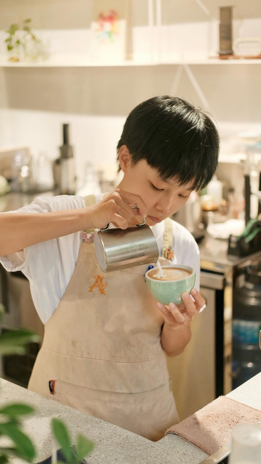 A barista pouring latte art into a cup