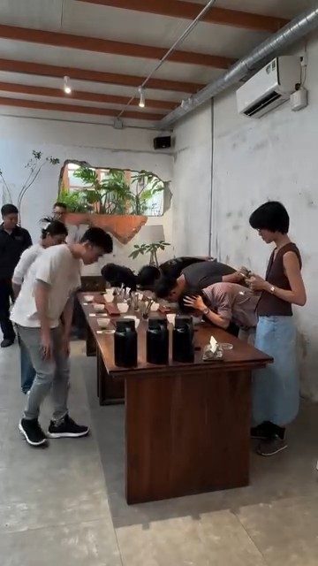 A community cupping around the wooden table
