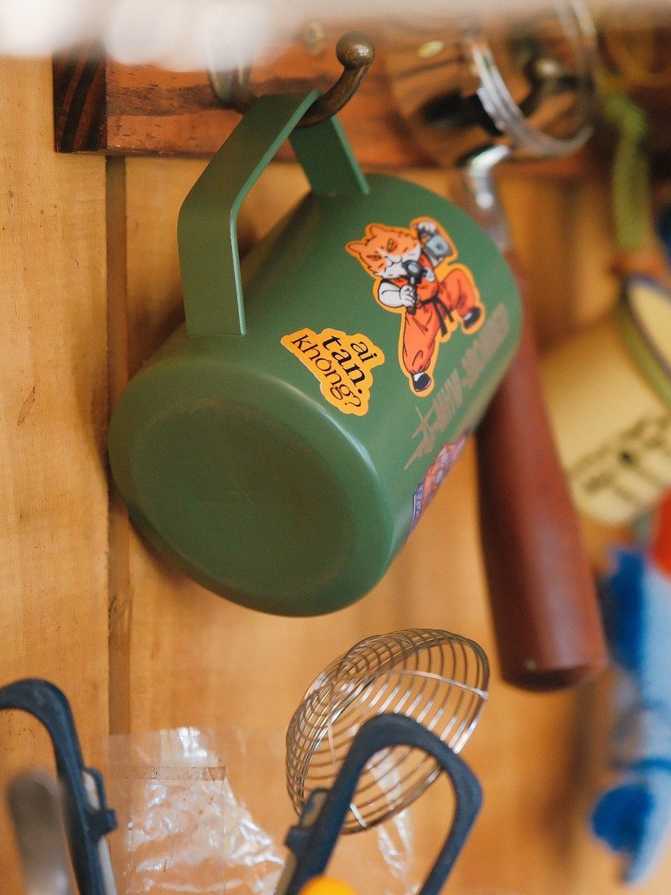 Close-up of a hanging tin mug with a cartoon-cat sticker