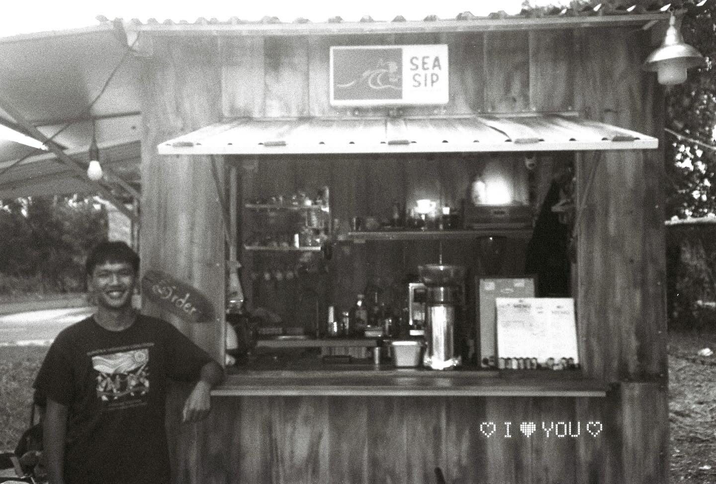 Black-and-white portrait of the owner behind the counter, next to an 'I ♥ YOU' sign